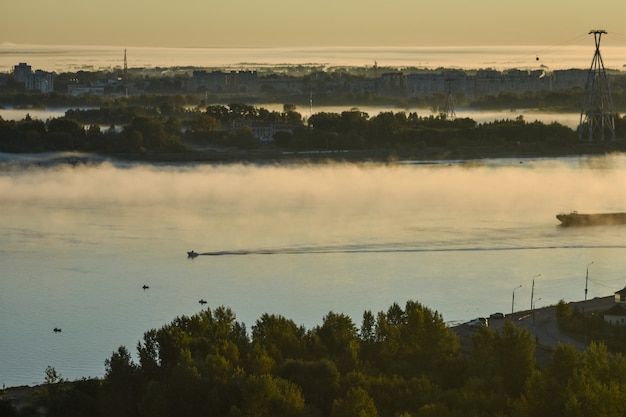 BOAT FLOATS ON THE RIVER THROUGH FOG