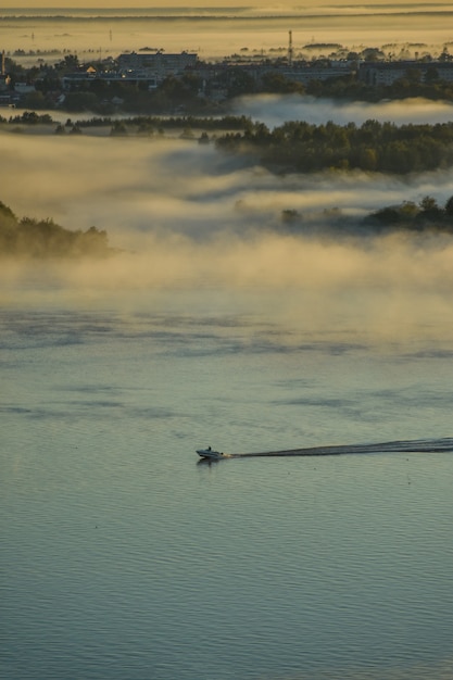 La barca galleggia sul fiume attraverso la nebbia