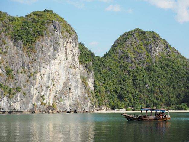 Foto barca sulla baia di halong vicino alle montagne rocciose