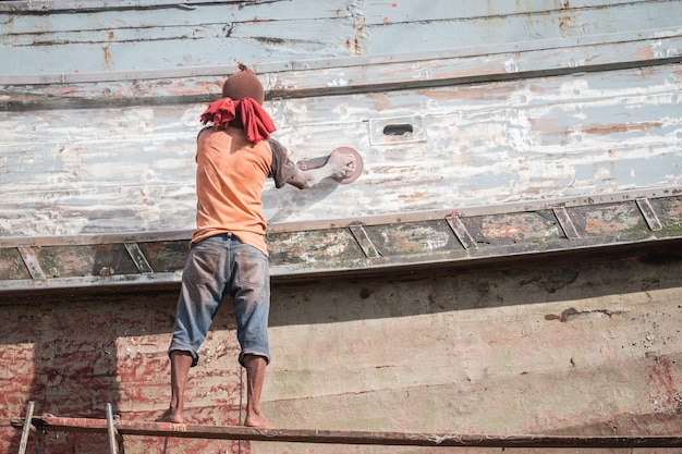 Boat Hull repairs/ A man using grinder in preparation for anti foul paint being applied