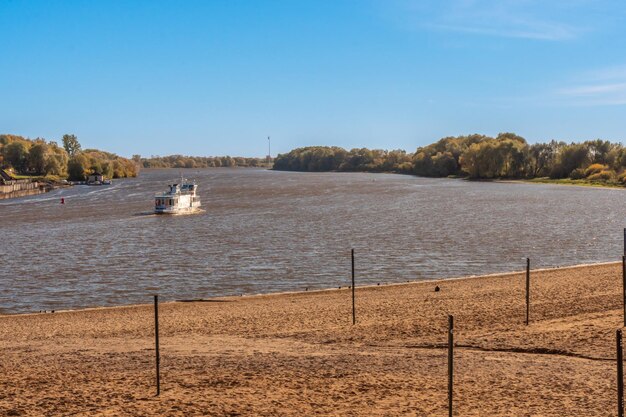 A boat is on the river in front of a fence.