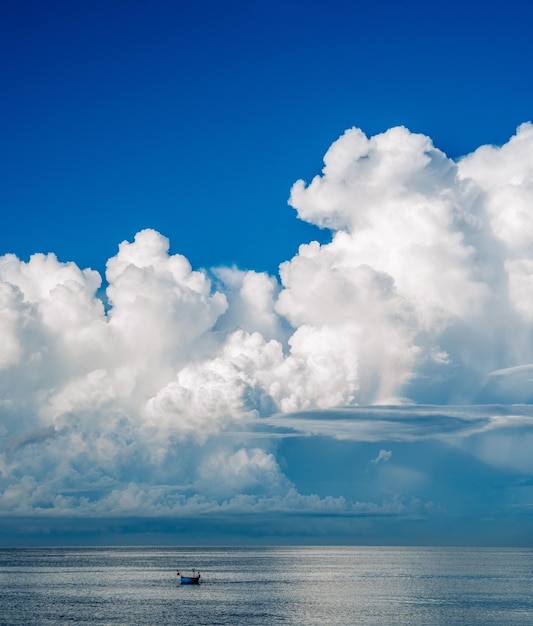 A boat is sailing in the ocean with a large cloud in the sky.