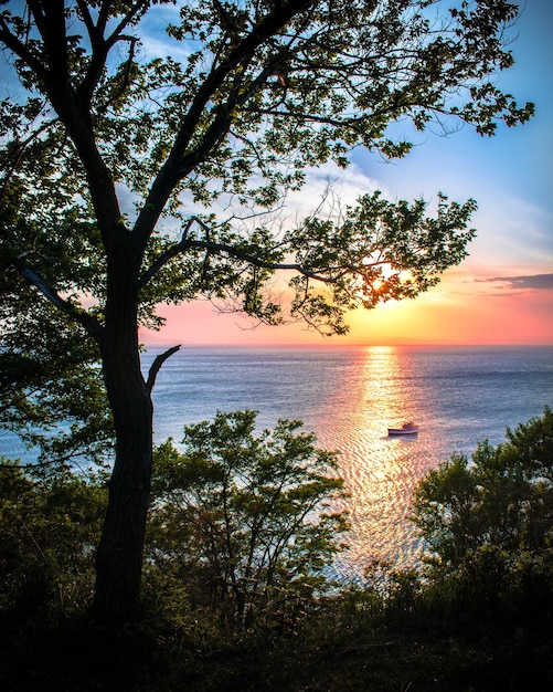 A boat is sailing on the water at sunset.