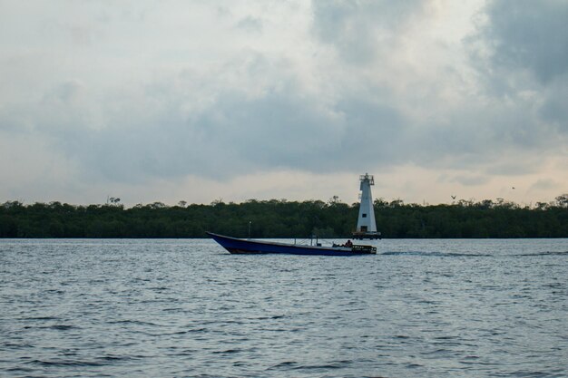 Photo a boat is sailing on the water with a light house on the top.