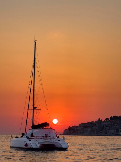 a boat is sailing in the water with the sun setting behind it