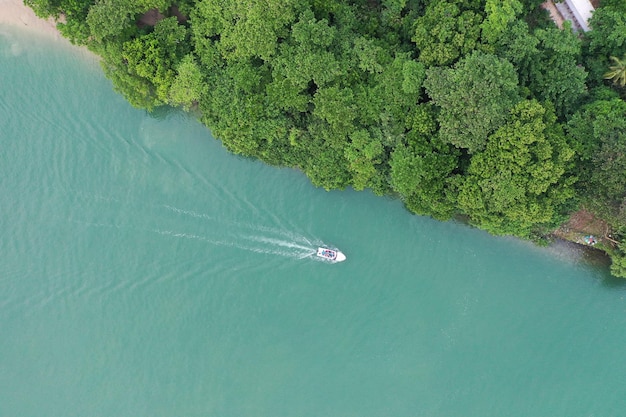 A boat is sailing on the water with trees in the background.