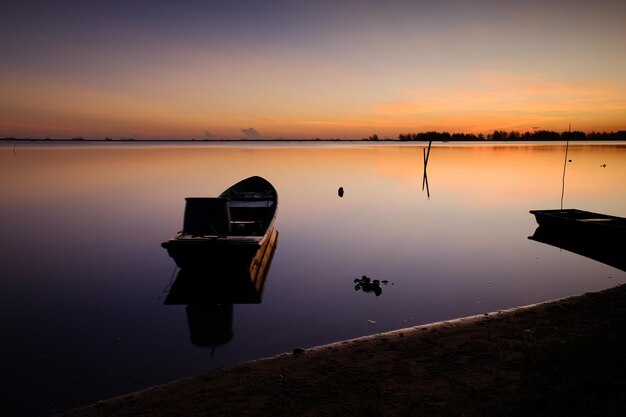 A boat is sitting in the water at sunset.