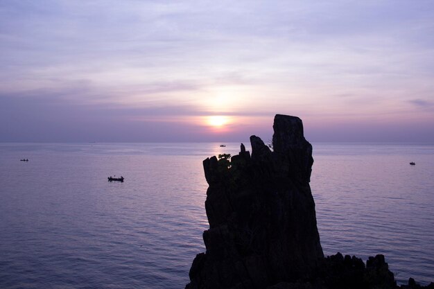 Foto una barca è in acqua con il sole che tramonta dietro di essa.