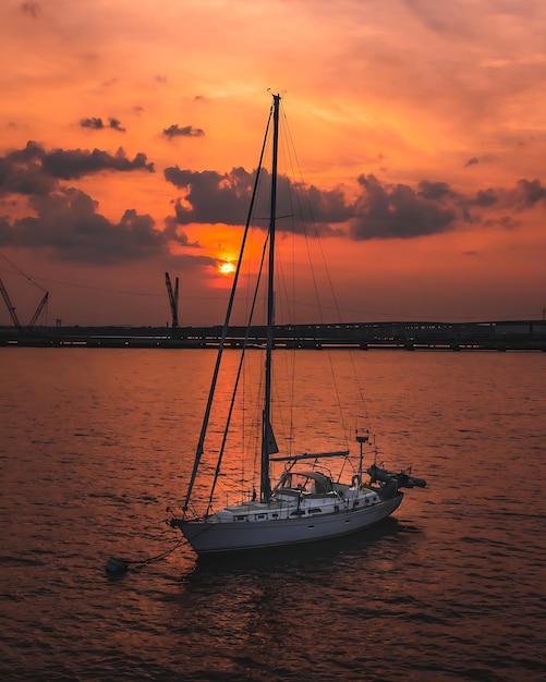 A boat is in the water with the sun setting behind it.