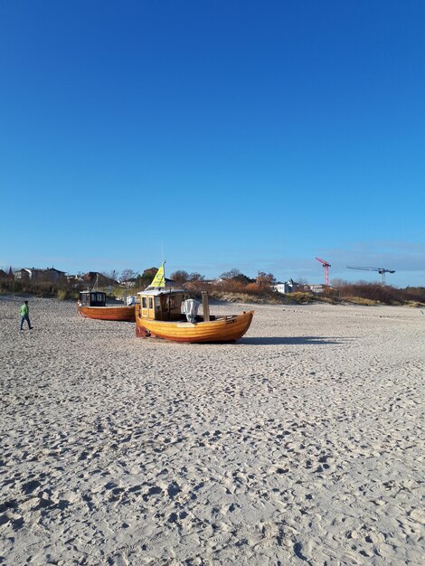 Boat moored on beach against clear blue sky