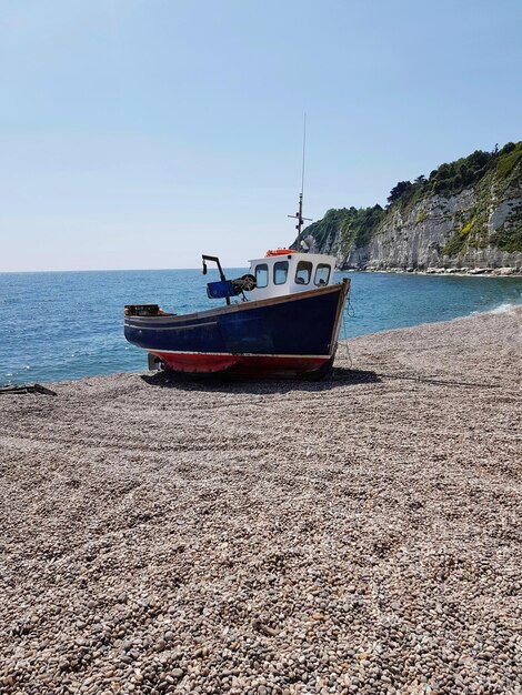 Boat moored on beach against clear sky