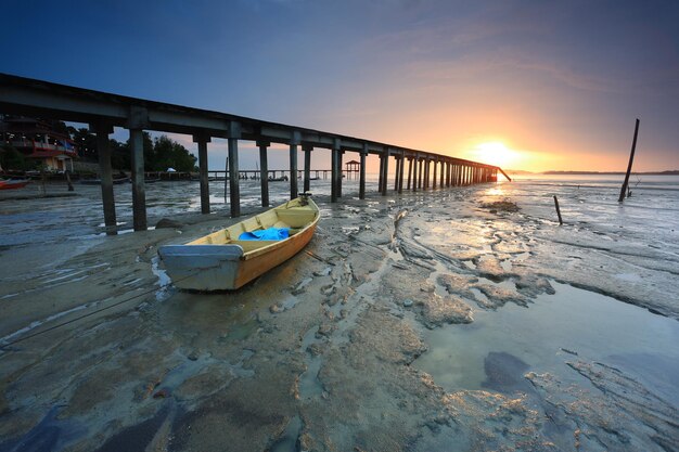 Photo boat moored on beach against sky during sunset