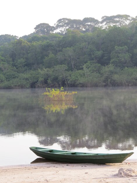 Boat moored in calm lake against mountain range