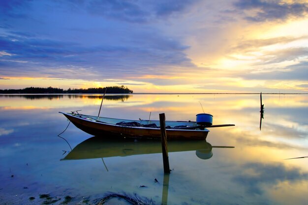 Boat moored in lake against sky during sunset