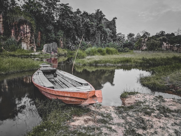 Photo boat moored on lake by trees against sky