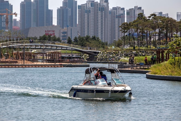 사진 도시 에 대항 한 공원 에 있는 호수 에서 보트 가 이동 하고 있다