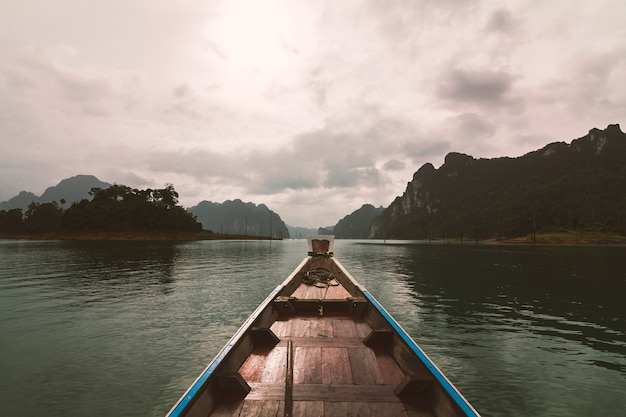 The boat sailed forward with a view of mountains and clouds