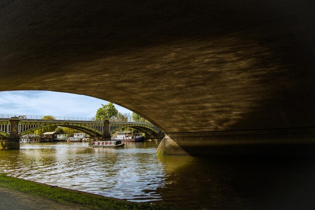 Boat sailing in river by arch bridge against sky