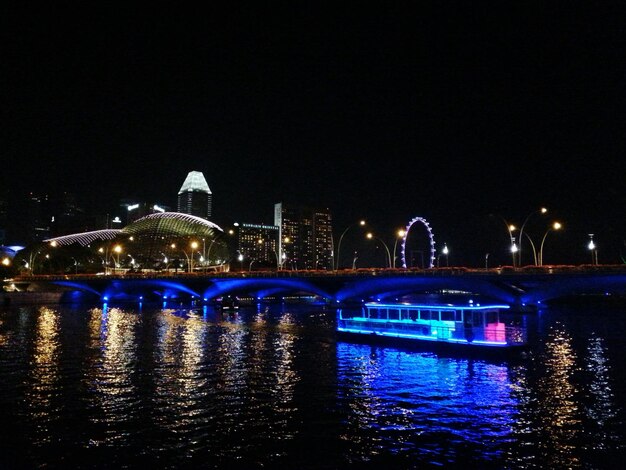 Photo boat sailing in river by illuminated bridge at night