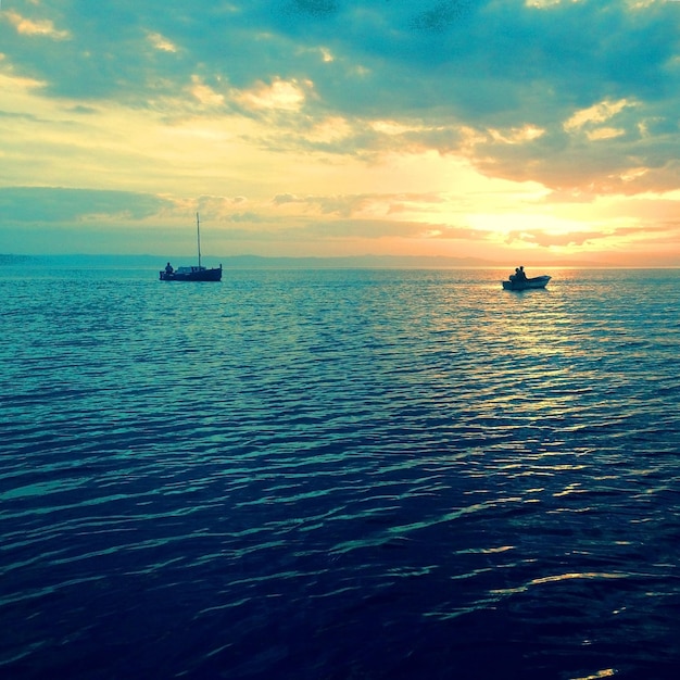 Foto una barca che naviga in mare al tramonto
