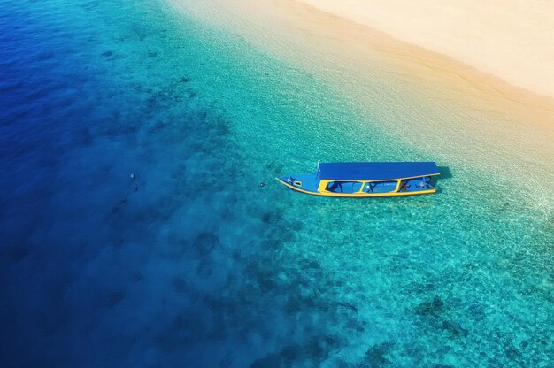 インドネシア バリ島の海でボート 晴れた日に透明なターコイズ ブルーの水に浮かぶボートの空撮 ドローンからのトップ ビュー 湾にモーター ボートがある海の風景