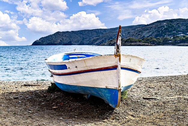 Photo a boat on the shore is painted in white and blue