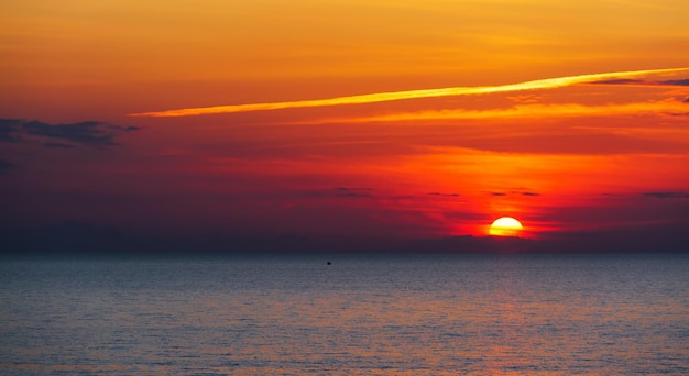 Boat silhouette alone in the sea under a scenic sky at sunset