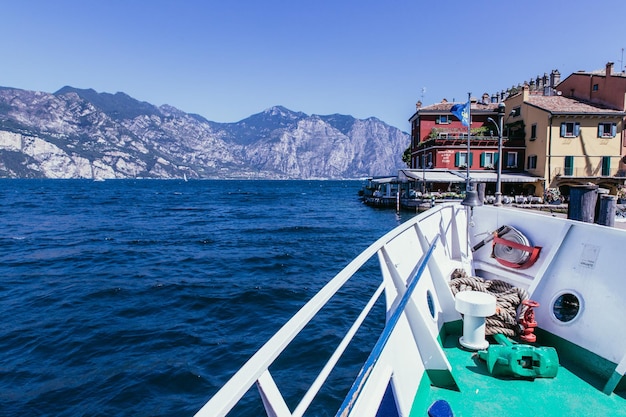 보트 투어 하늘색 푸른 물 마을과 산맥 Lago di Garda 이탈리아 위로 보트 보우 뷰