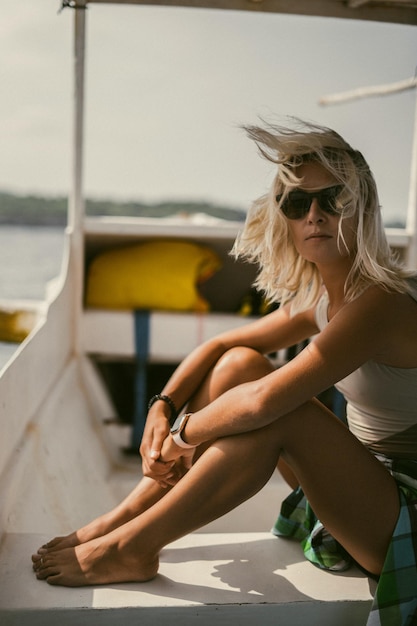 Boat trip in bali. a young woman in sunglasses is sailing on a\
boat to a nearby island.