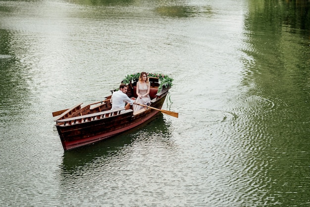 野生の柳が生い茂る川の運河と湾に沿った男と女のボートトリップ