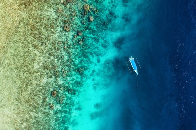 Boat on the water surface from top view Turquoise water background from top view Summer seascape from air Gili Meno island Indonesia Travel image