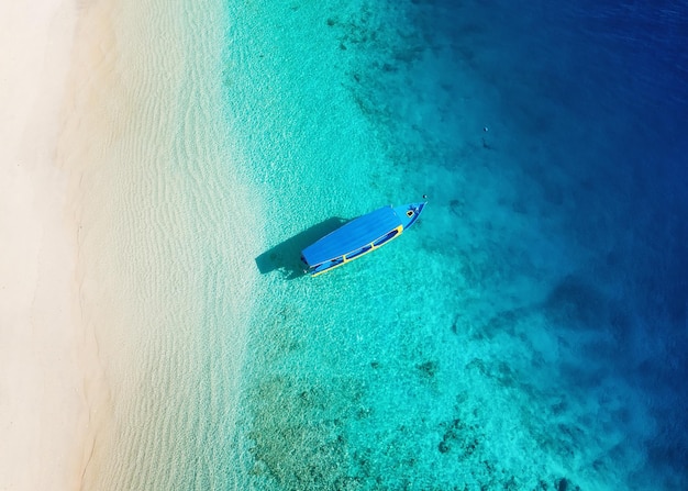 Boat on the water surface from top view Turquoise water background from top view Summer seascape from air Gili Meno island Indonesia Travel image