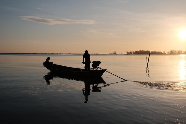 A boat in the water with a man standing in front of it