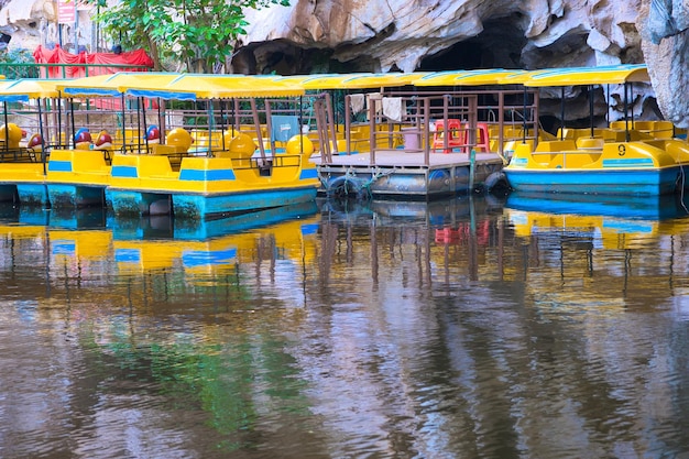 A boat with a blue roof is docked next to a cave.