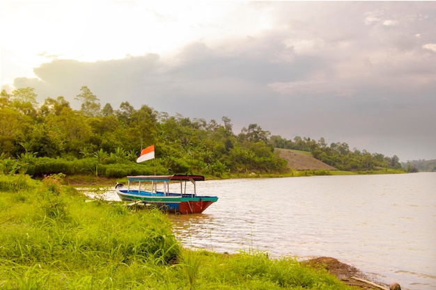 boat with indonesian flag on river natural background and cloudy sky.