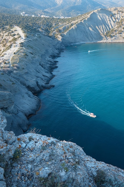 Boat with passengers at sea, summer vacation, yacht trip in the middle of rocks and mountains, seascape