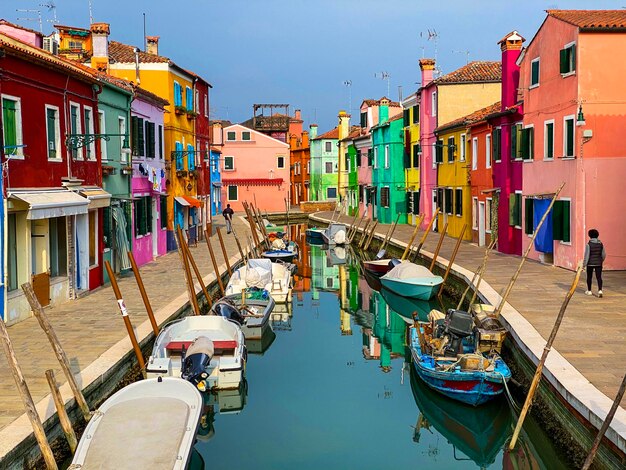 Boats docking and colorful houses in a canal street houses on Burano island Venice One unrecognizable people on the background