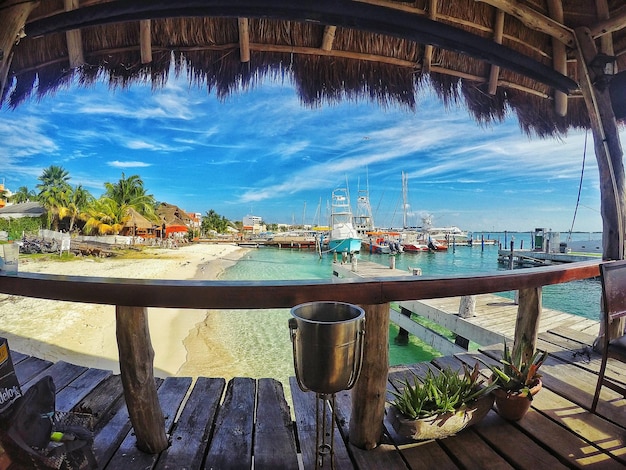 Photo boats at harbor seen from thatched roof pier