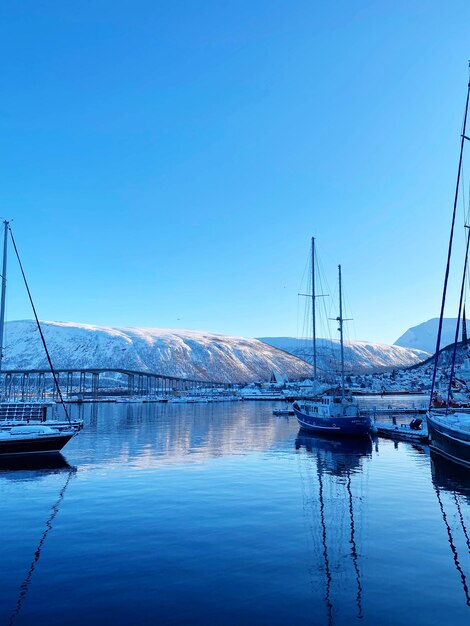 Boats in harbor tromso sea norway snow reflection sunny sunset blue clear water sailing equipment