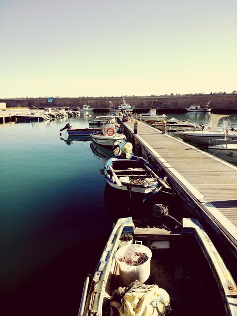 Photo boats moored by pier in lake against sky