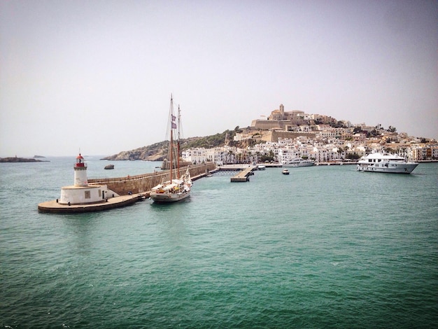 boats moored by town against sky