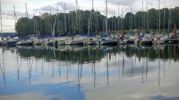 Boats moored in calm lake against sky