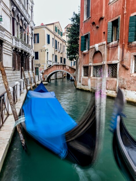 Boats moored in canal amidst buildings in city