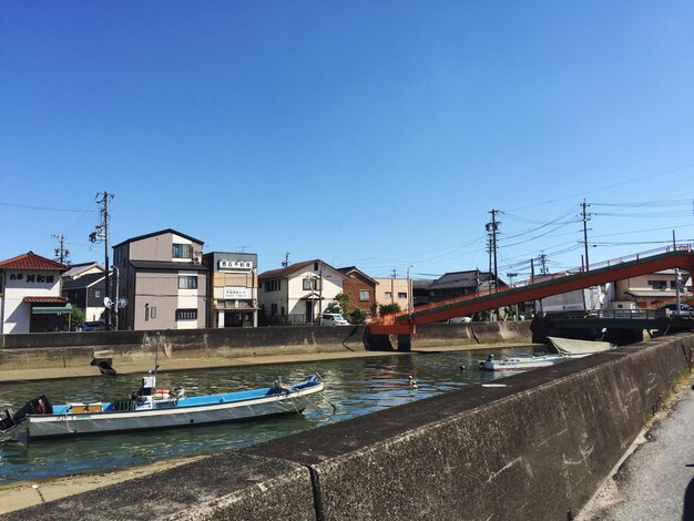 Boats moored in city against clear blue sky