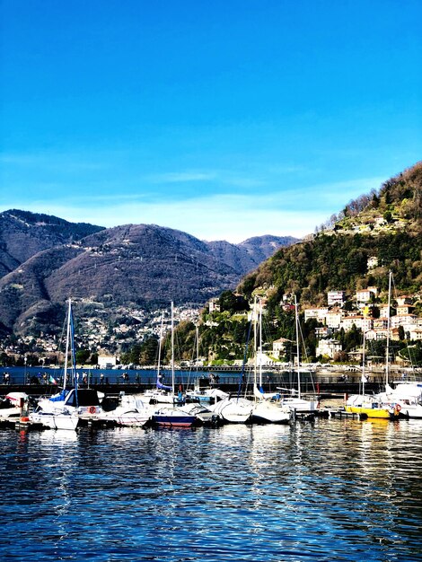 Boats moored at harbor against blue sky