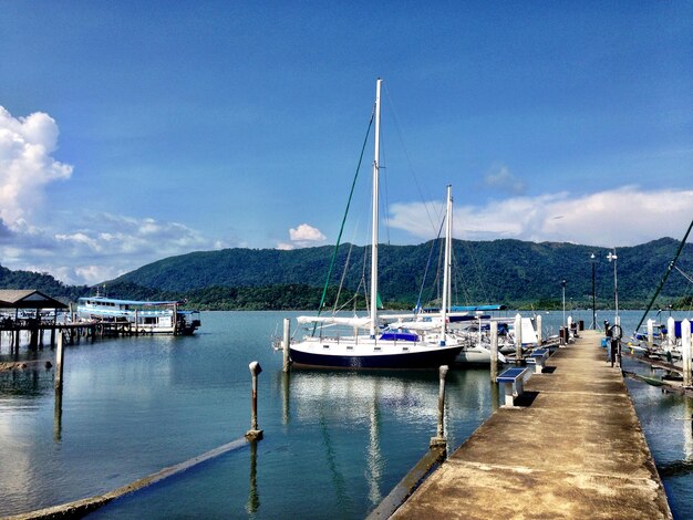 Boats moored at harbor against blue sky