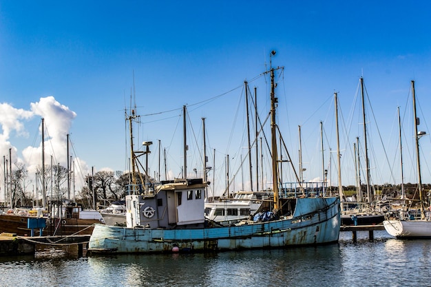 Boats moored at harbor against blue sky