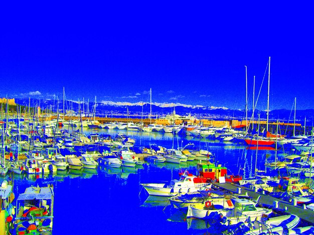 Boats moored in harbor against clear blue sky