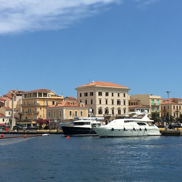 Boats moored at harbor against clear blue sky