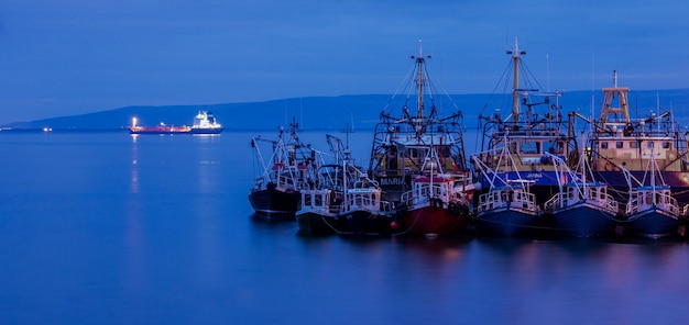 Boats moored at harbor against sky at dusk